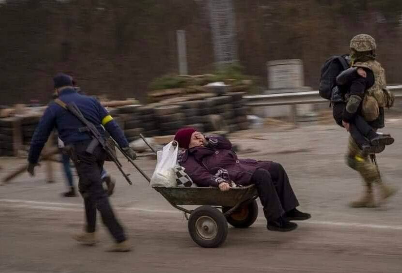 Oudere Oekraïners worden in kruiwagens meegenomen.